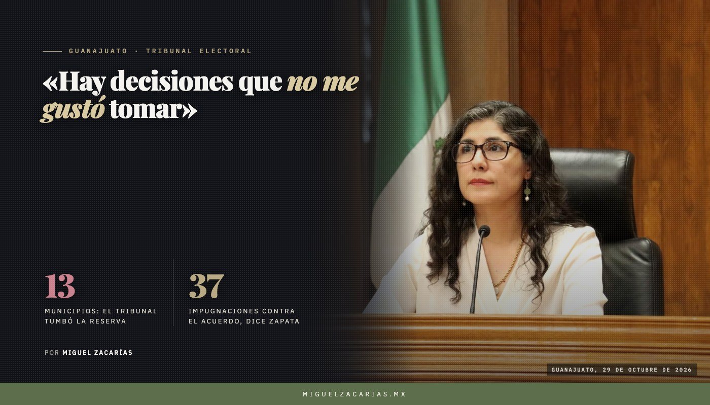 Una mujer de cabello oscuro y lentes, con saco blanco, sentada tras un estrado de madera frente a un micrófono; a su izquierda, una bandera de México.